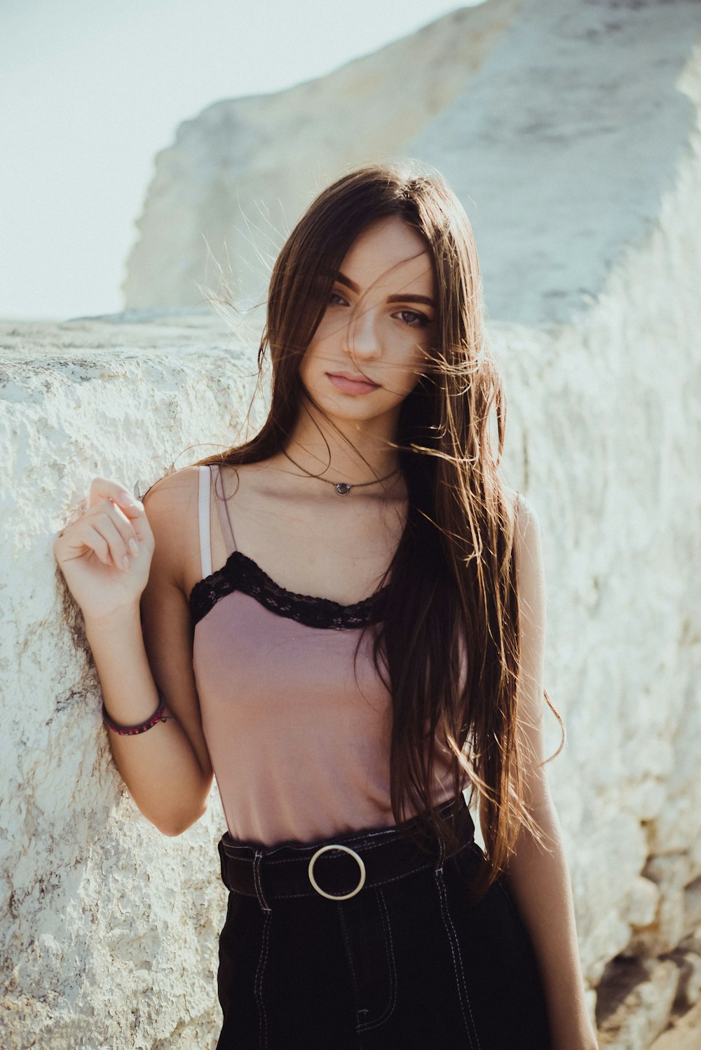 woman wearing gray and black camisole standing beside wall