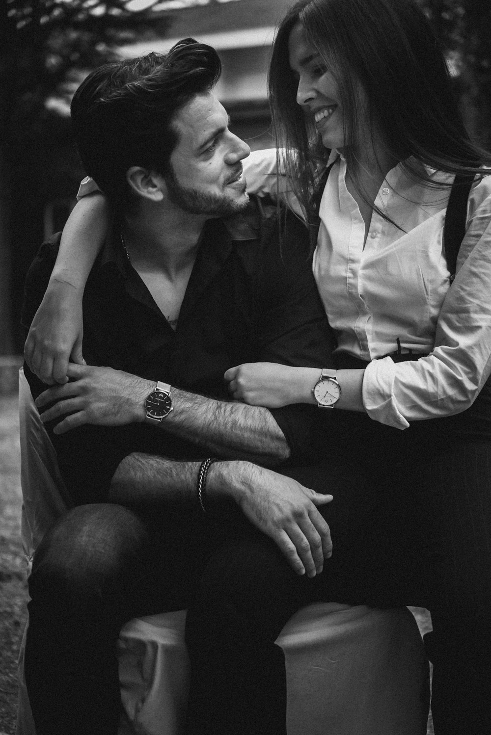 grayscale photography of couple sitting on chair while looking each other