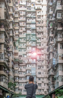 man standing fronting high-rise building