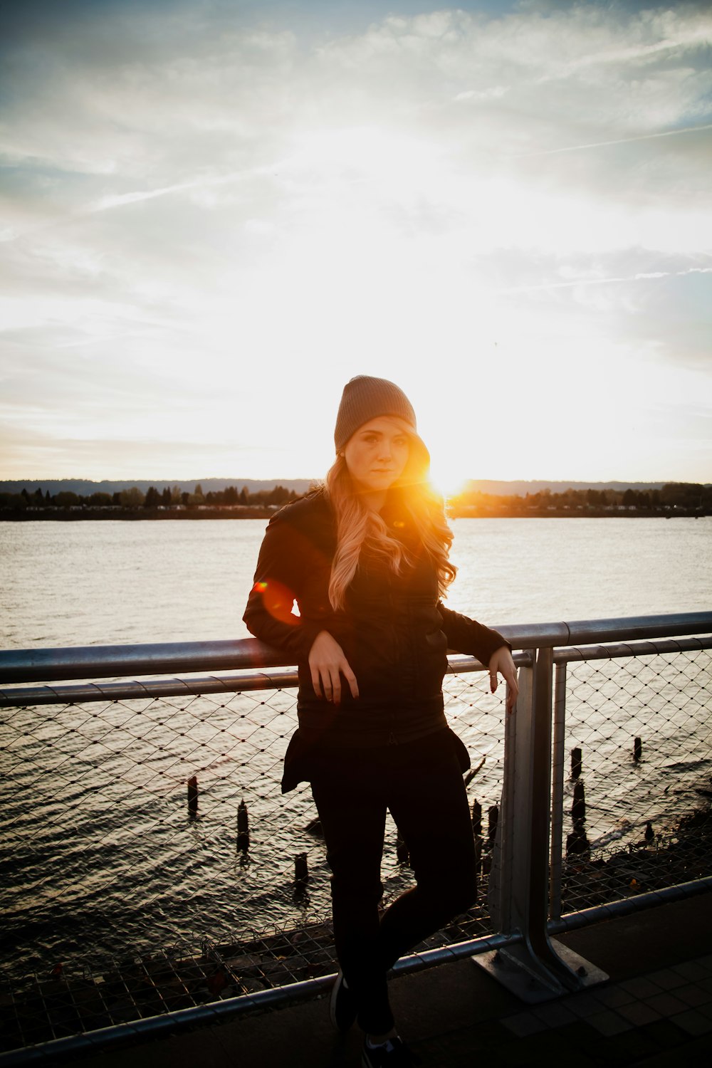 woman leaning on fence near body of water