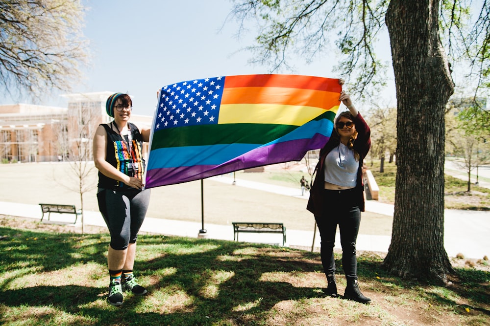 two woman holding multicolored flag