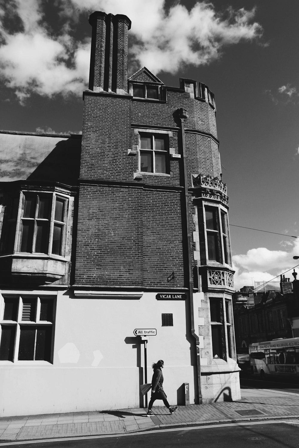 grayscale photography of person walking on street beside building