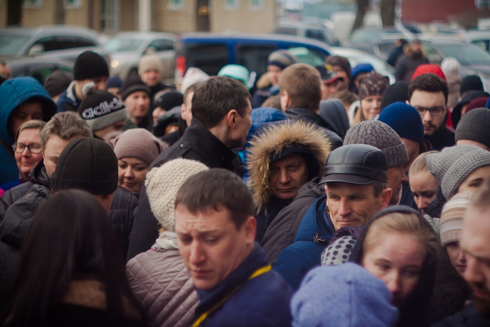 selective focus photography of person wearing black parka coat surrounded by group of people