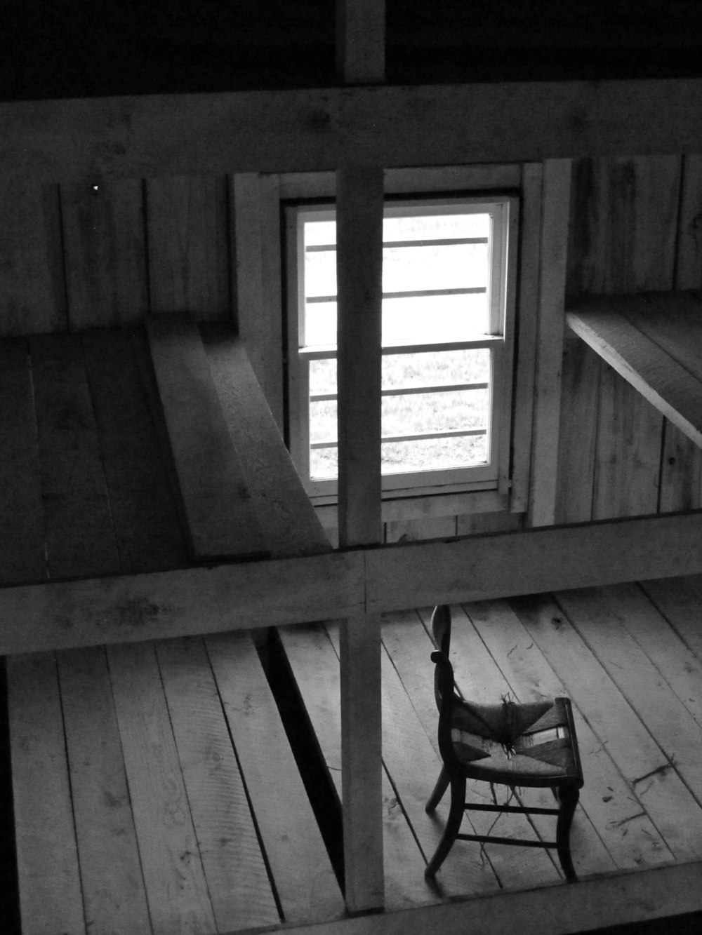 grascale photo of chair near window inside room