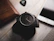 A sleek wristwatch resting on a wooden table beside a leather bag.