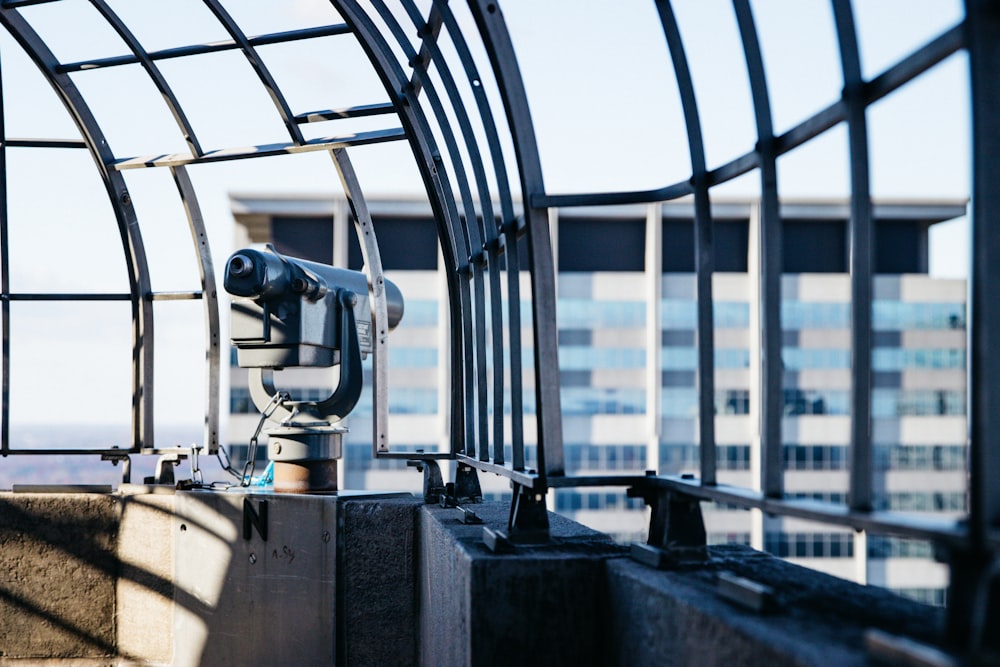 Telescopio gris y negro al lado de la barandilla