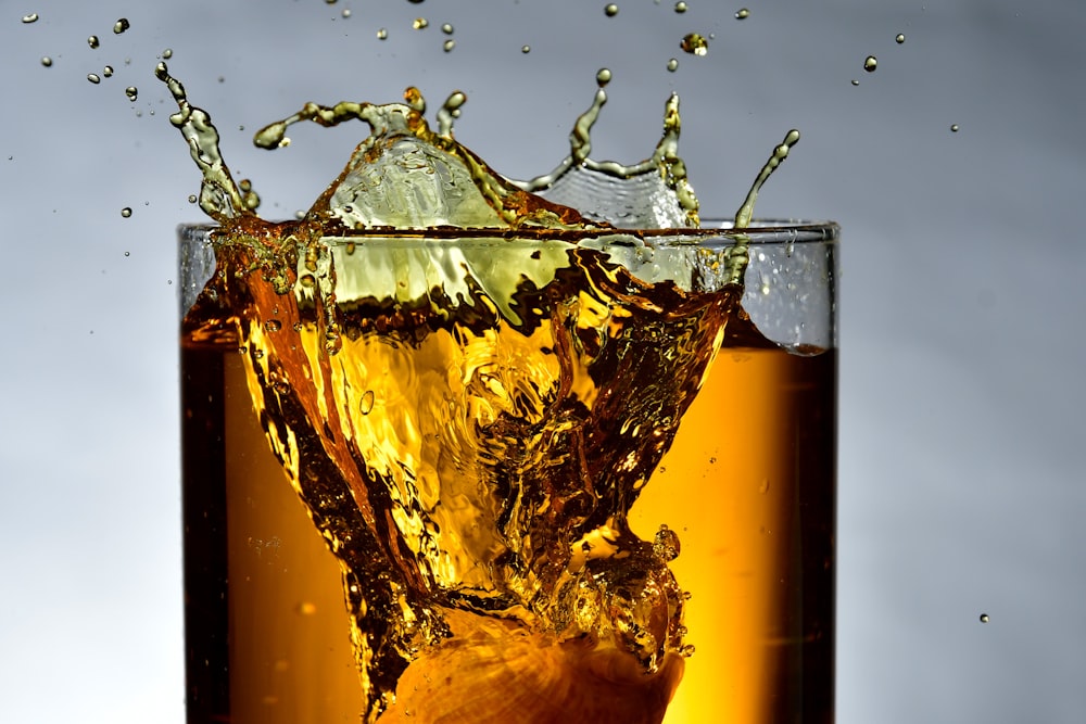verre à boire transparent rempli d’un liquide brun