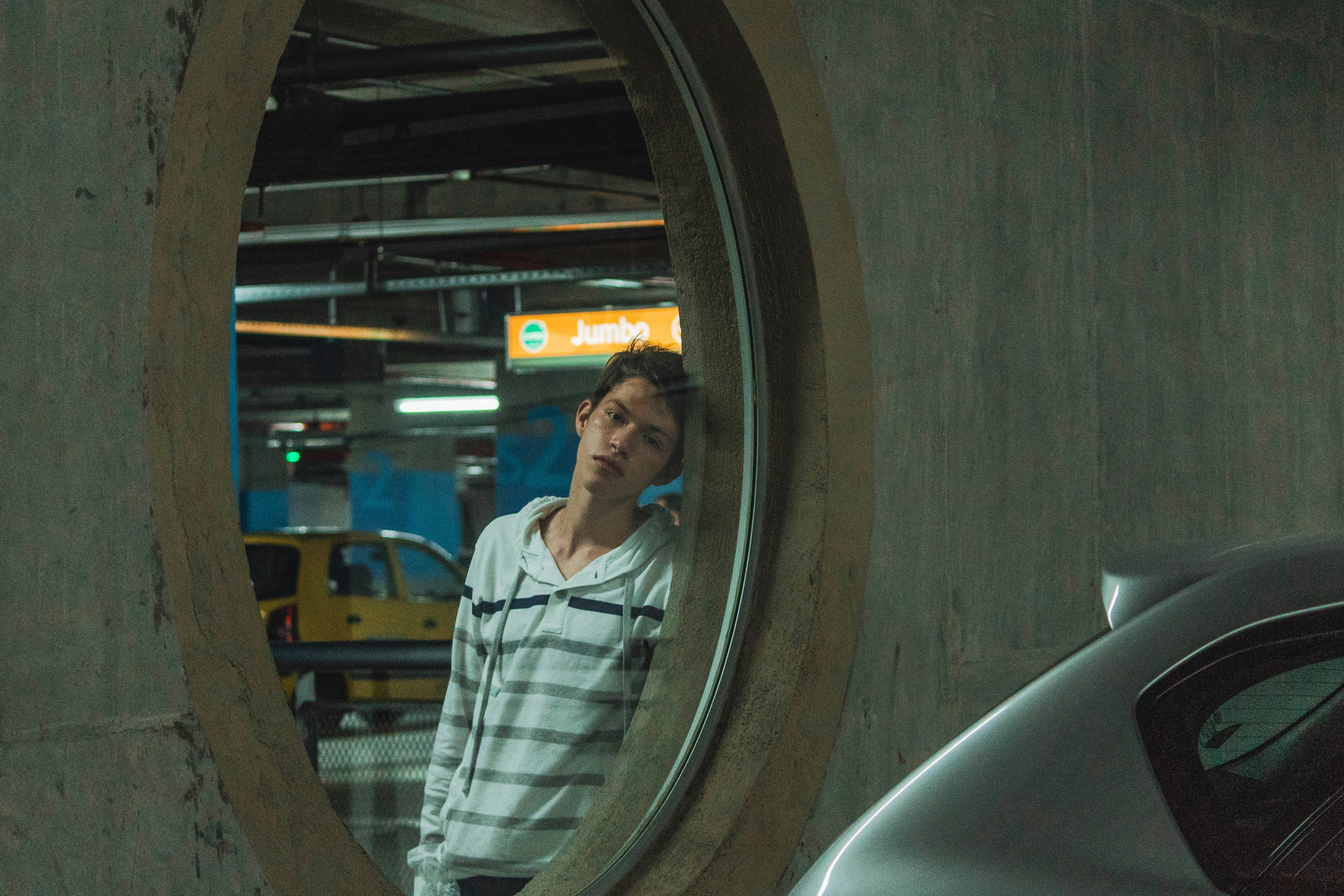 man standing beside gray wall