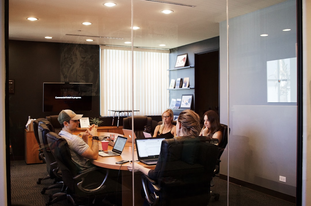 People sitting at a conference table with laptops discussing the benefits of embedded reporting