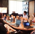 man standing in front of people sitting beside table with laptop computers