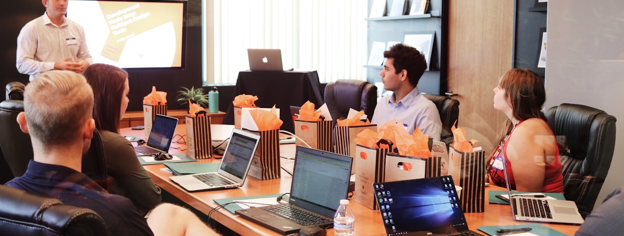 man standing in front of people sitting beside table with laptop computers