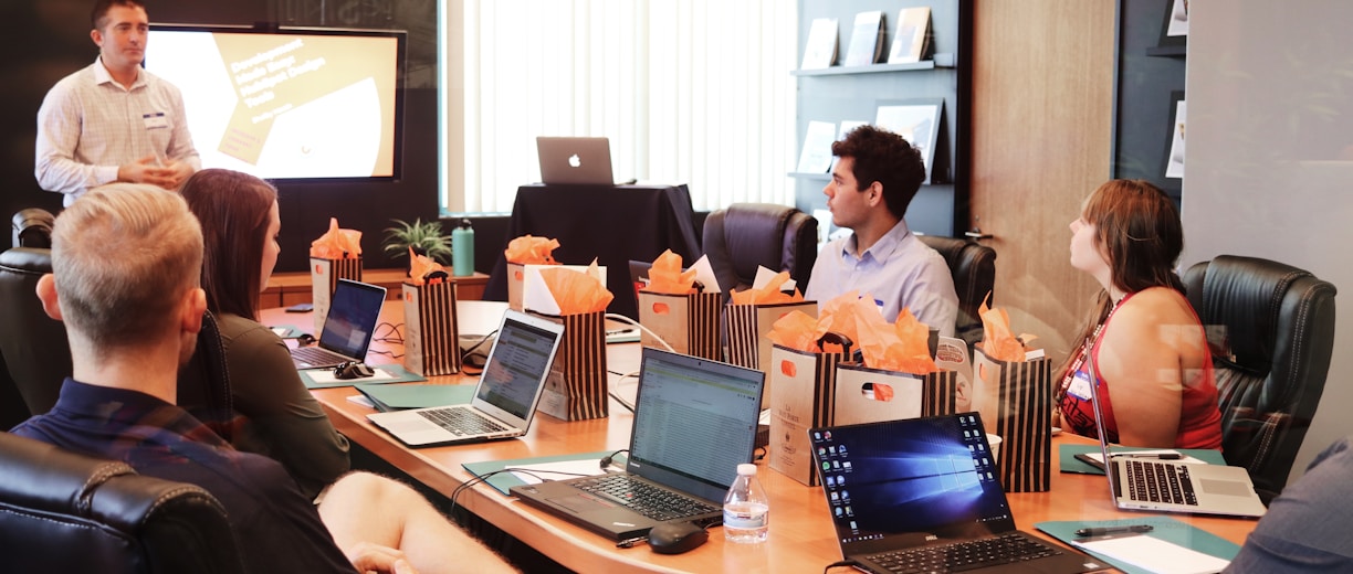 man standing in front of people sitting beside table with laptop computers