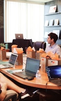 man standing in front of people sitting beside table with laptop computers