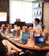 man standing in front of people sitting beside table with laptop computers