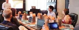 man standing in front of people sitting beside table with laptop computers