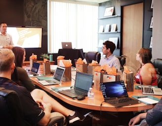 man standing in front of people sitting beside table with laptop computers