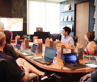 man standing in front of people sitting beside table with laptop computers