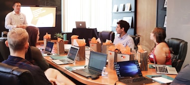 man standing in front of people sitting beside table with laptop computers