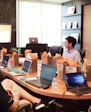 man standing in front of people sitting beside table with laptop computers