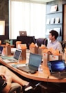 man standing in front of people sitting beside table with laptop computers