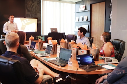 man standing in front of people sitting beside table with laptop computers