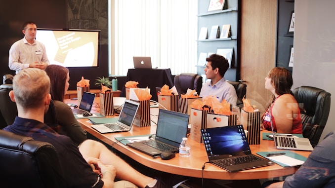 man standing in front of people sitting beside table with laptop computers