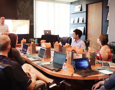 man standing in front of people sitting beside table with laptop computers