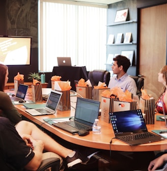 man standing in front of people sitting beside table with laptop computers