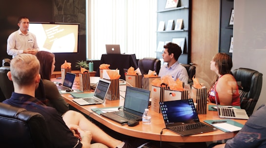 man standing in front of people sitting beside table with laptop computers