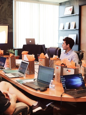 man standing in front of people sitting beside table with laptop computers