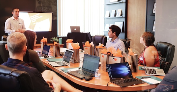 man standing in front of people sitting beside table with laptop computers