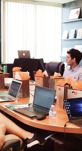 man standing in front of people sitting beside table with laptop computers