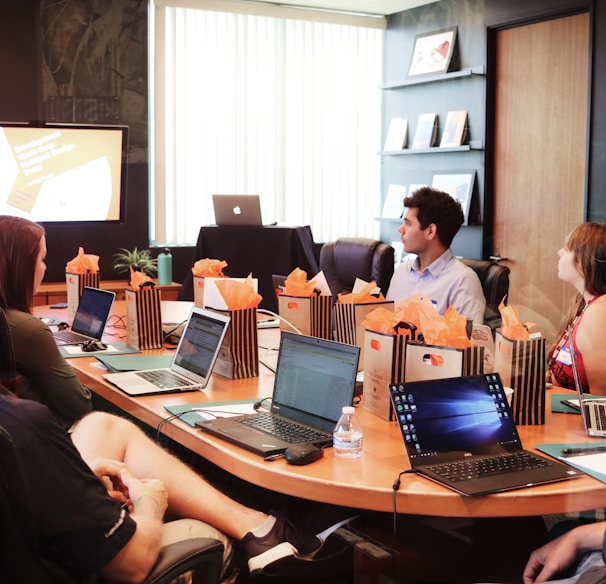 man standing in front of people sitting beside table with laptop computers