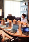 man standing in front of people sitting beside table with laptop computers