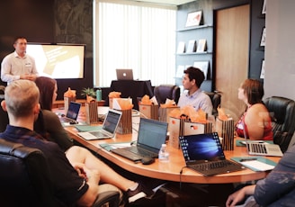 man standing in front of people sitting beside table with laptop computers