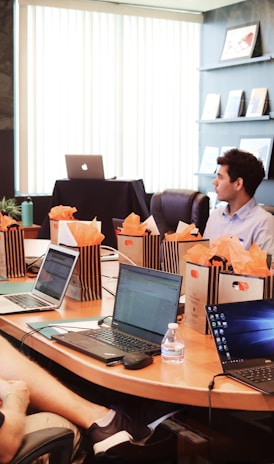 man standing in front of people sitting beside table with laptop computers