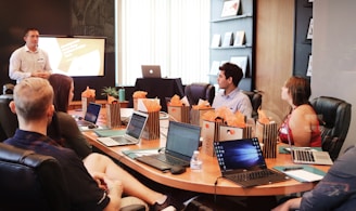 man standing in front of people sitting beside table with laptop computers