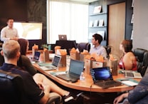 man standing in front of people sitting beside table with laptop computers