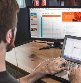 man wearing red earphone sitting on chair while using laptop