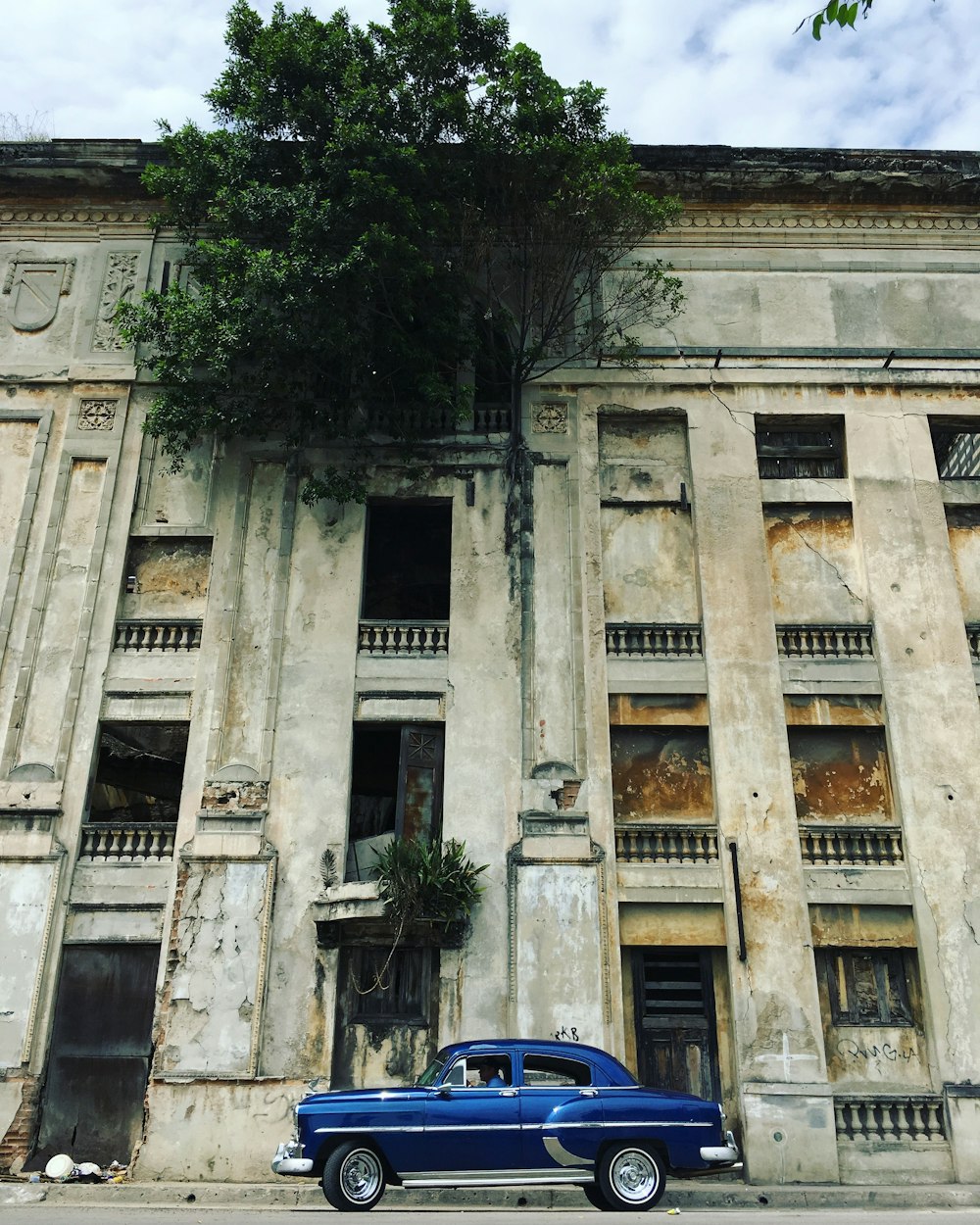 blue sedan parked in front of concrete building