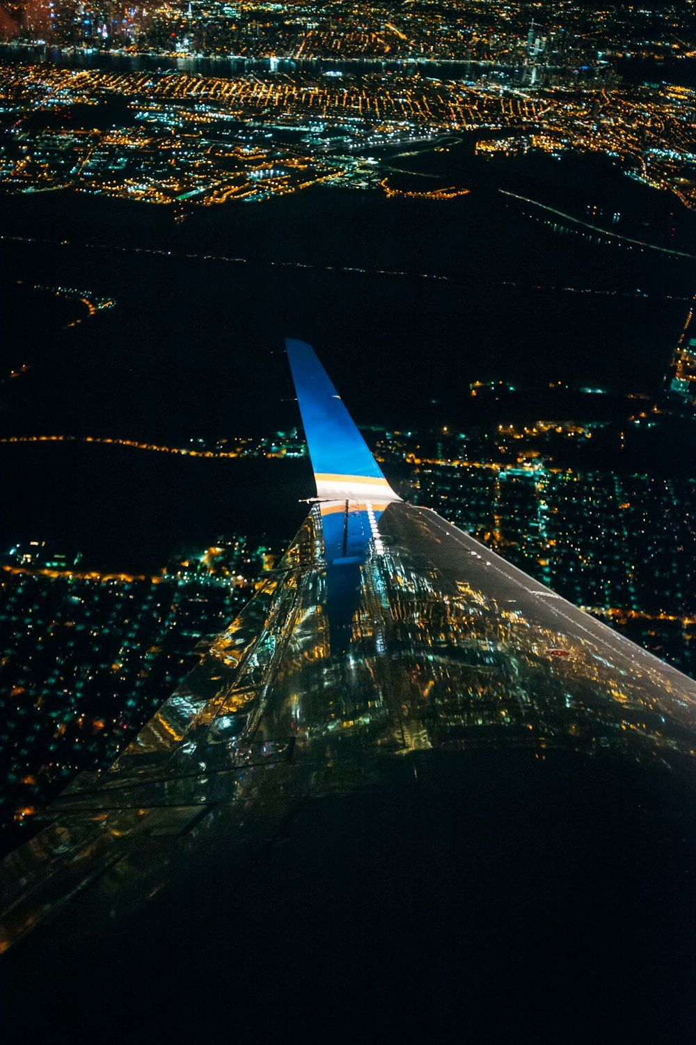 Ein Flugzeugflügel, der nachts über eine Stadt fliegt