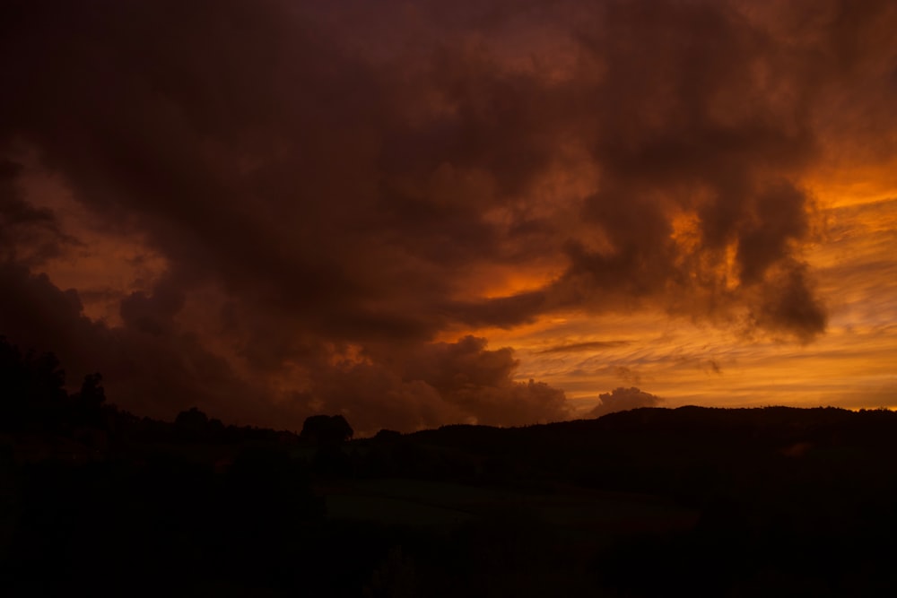 Una puesta de sol con nubes y árboles de fondo