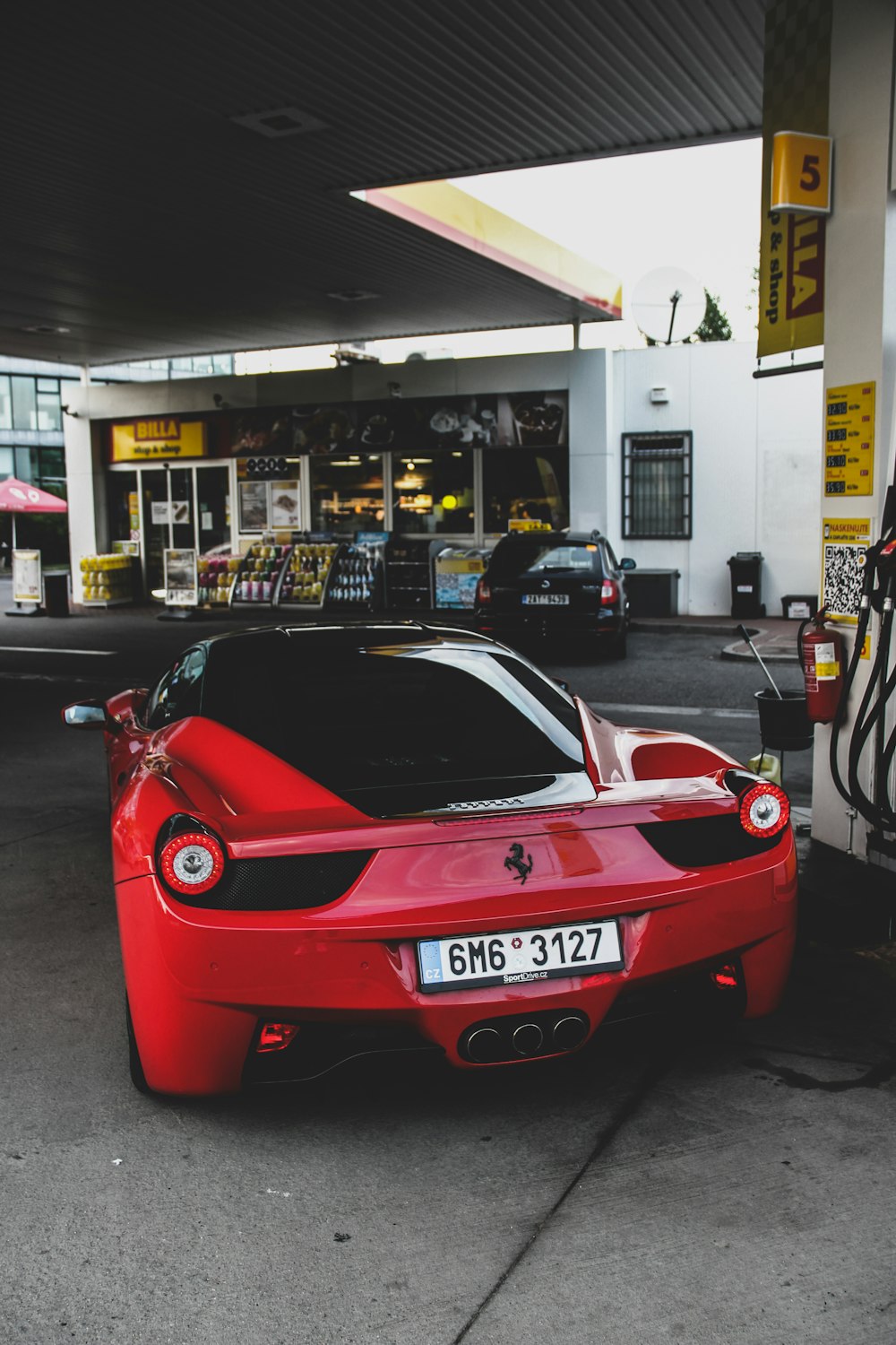 red coupe parked on gasoline station