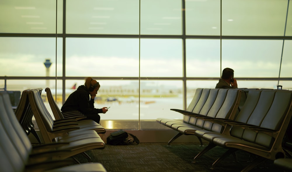 man and woman sitting on gang chair in airport