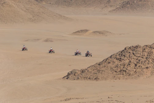 A group of adventurers gearing up for an off-road ATV tour on rugged desert trails.