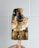 A hand holding a chocolate popsicle topped with toasted marshmallow and crumbled graham crackers. The popsicle has a partially melted, gooey texture with a bite taken out of it.