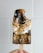 A hand holding a chocolate popsicle topped with toasted marshmallow and crumbled graham crackers. The popsicle has a partially melted, gooey texture with a bite taken out of it.