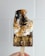 A hand holding a chocolate popsicle topped with toasted marshmallow and crumbled graham crackers. The popsicle has a partially melted, gooey texture with a bite taken out of it.