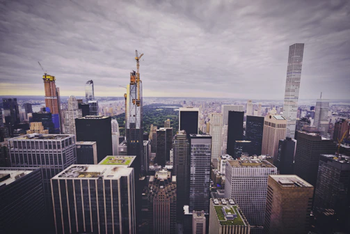 A panoramic view of a high-rise commercial building under construction with cranes.