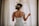 woman in wedding dress standing near window looking outside while holding the curtains